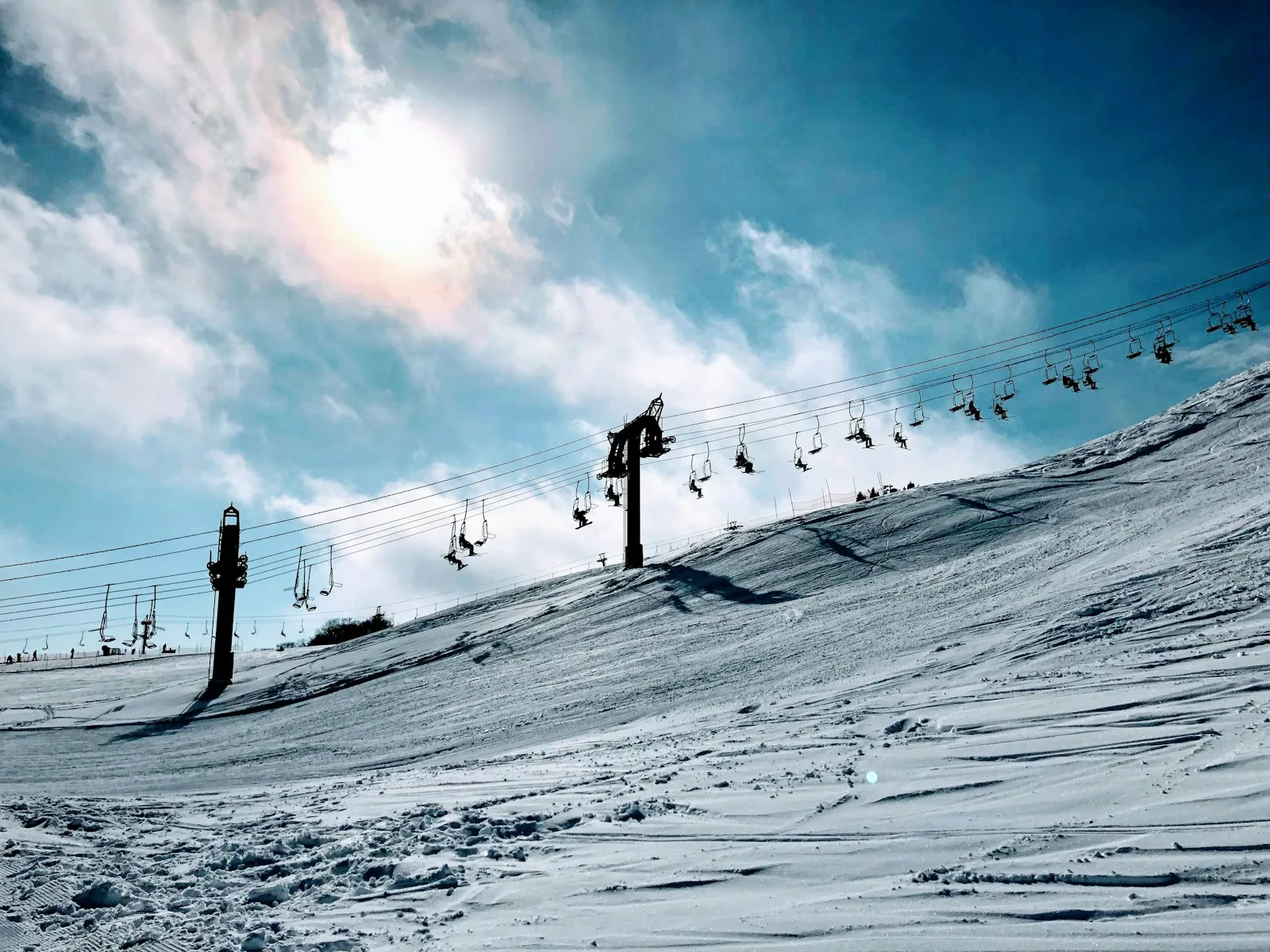 Snowy Japanese ski slope with a chairlift and skiers under a winter sky